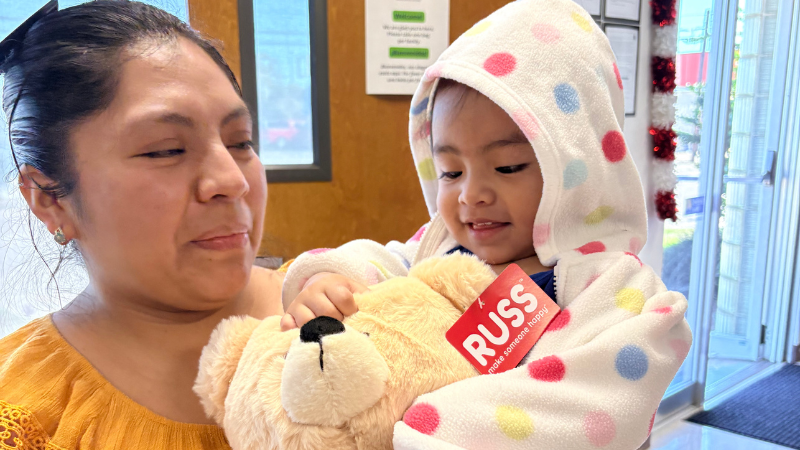 A photo of a mother and her child who are Catholic Charities clients. Both are smiling after receiving a special gift at their appointment.
